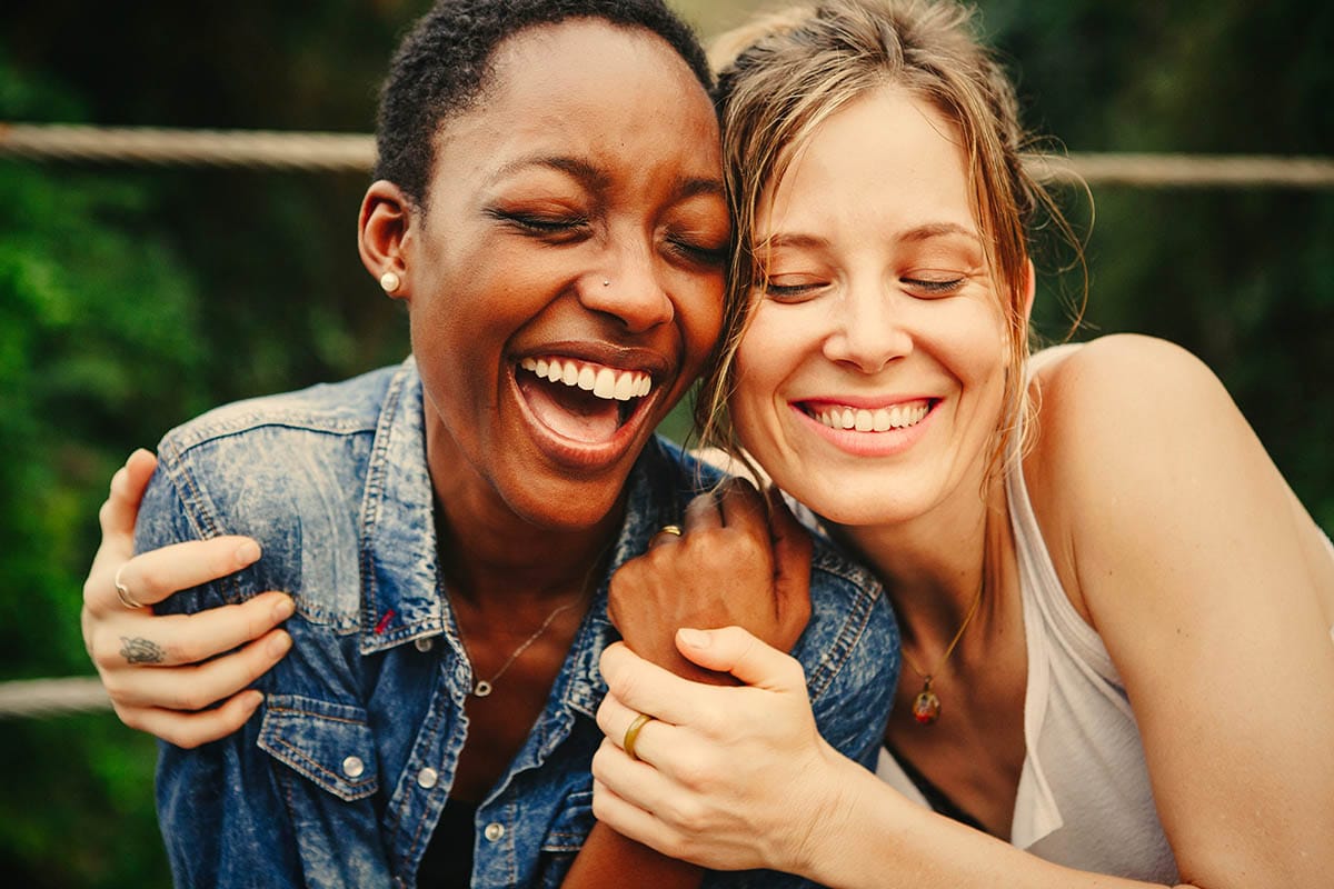 two women hugging and smiling while discussing how to quit alcohol safely