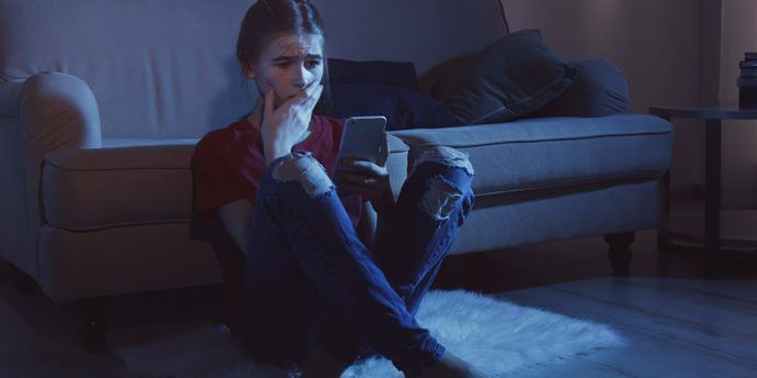 woman watching tv and reading about the signs of alcohol poisoning