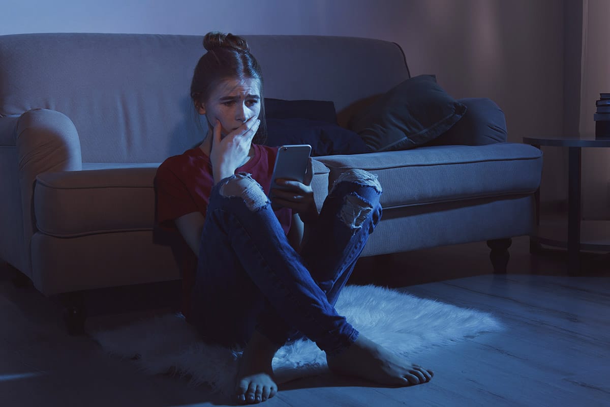 woman watching tv and reading about the signs of alcohol poisoning