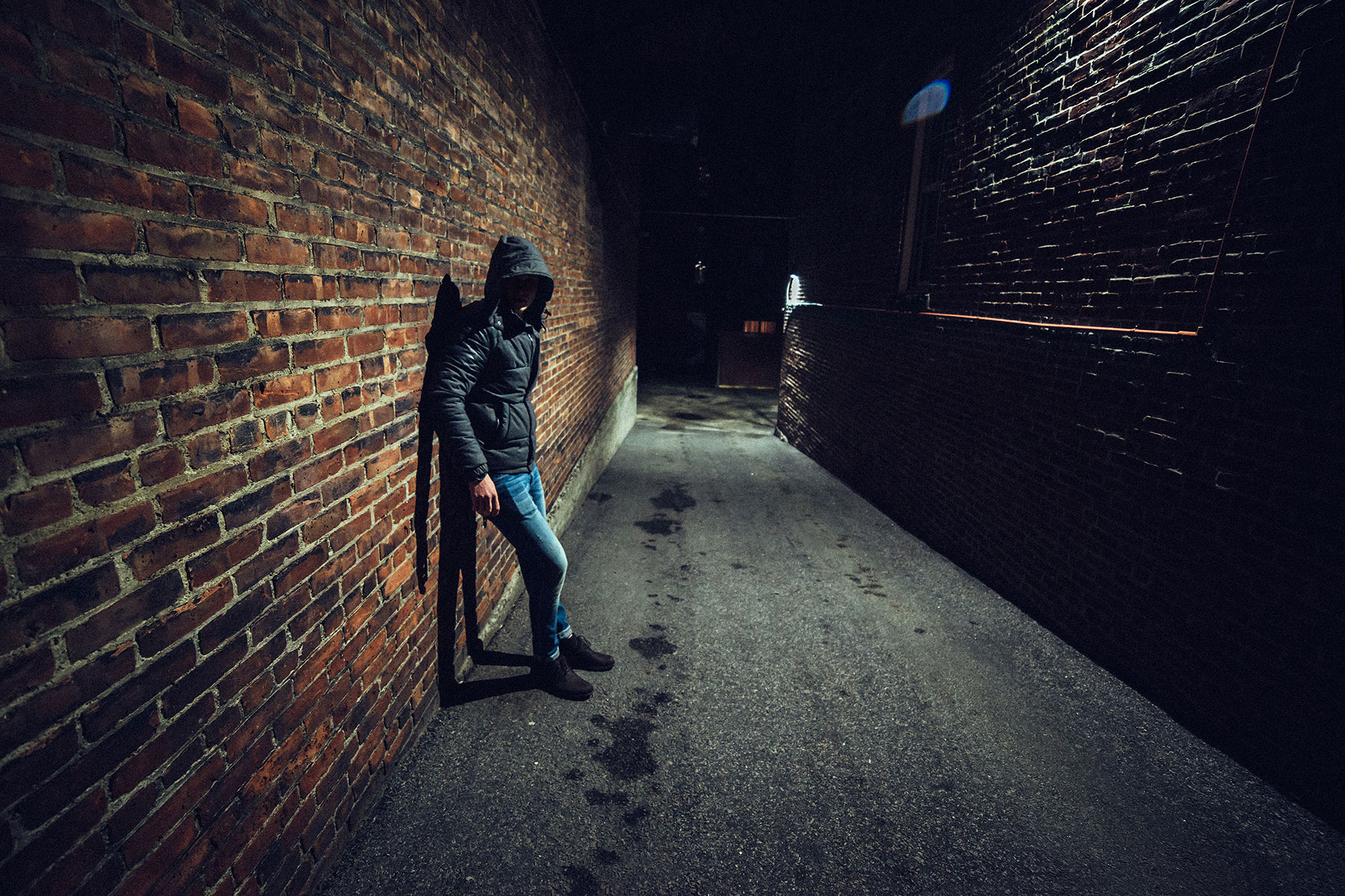 person in hoodie leaning against brick wall of dark alleyway while pondering the question what are the most dangerous drugs