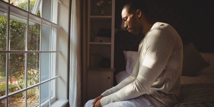 man sits in front of window and considers what does heroin withdrawal feel like