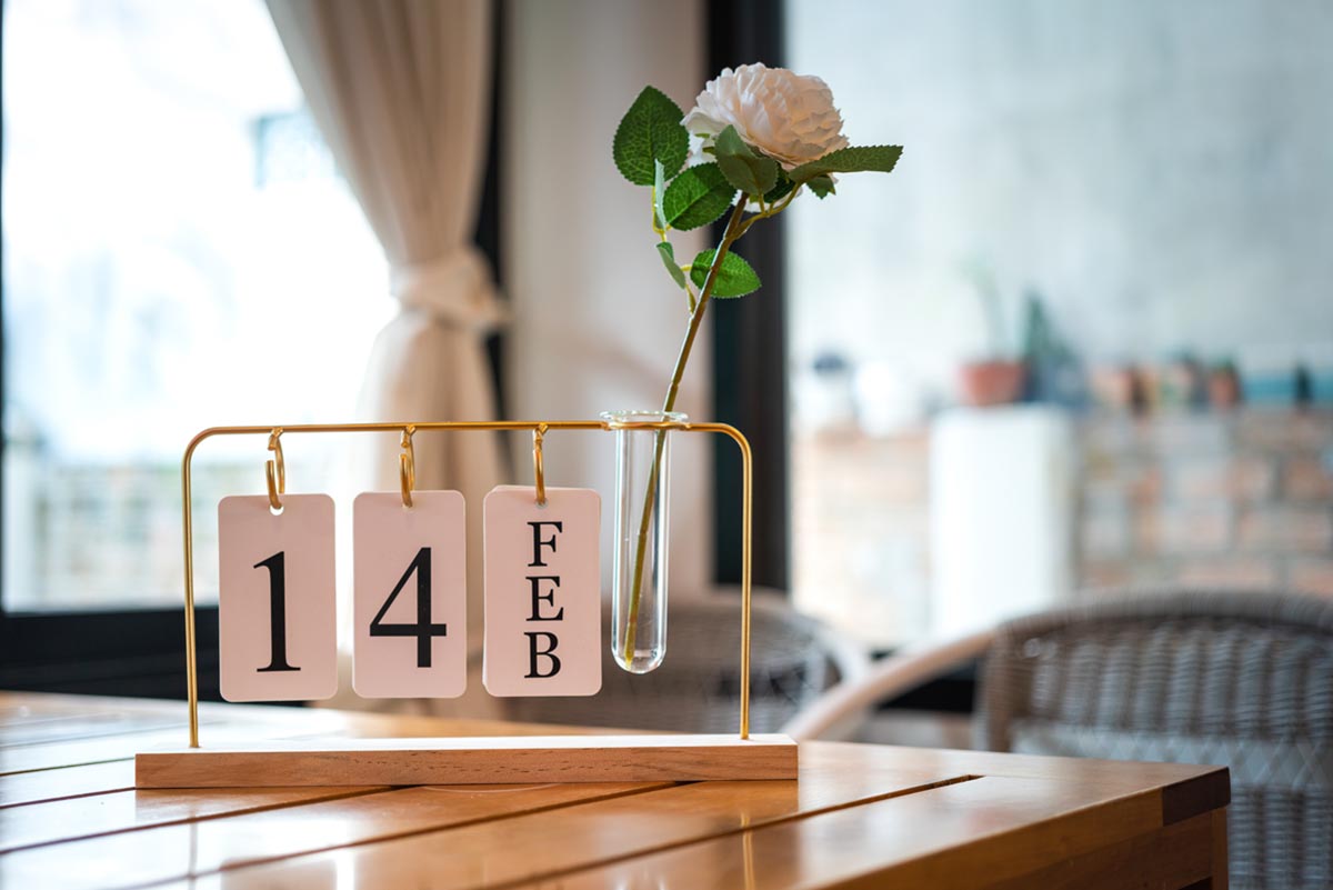 Calendar on table in rehab center displaying the date February 14th with a white rose to celebrate Valentine's Day in addiction recovery