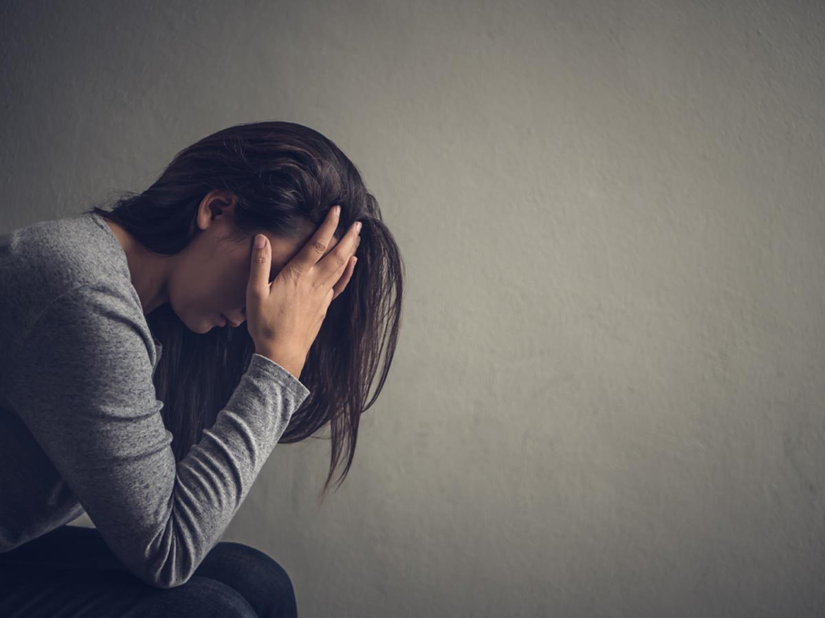 Side view of woman in despair covering face with hands while struggling with the mental effects of heroin addiction