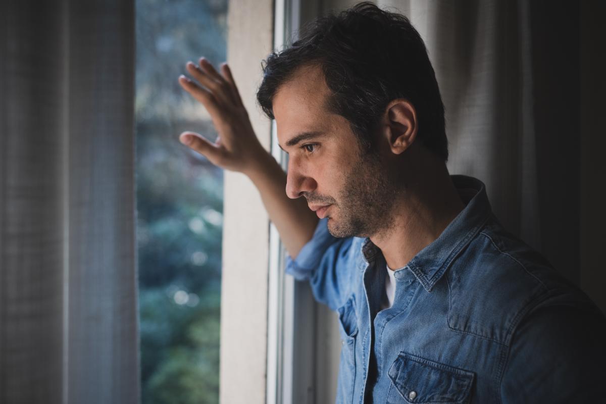 Pensive man looking out winder thinking about methadone vs suboxone treatment programs