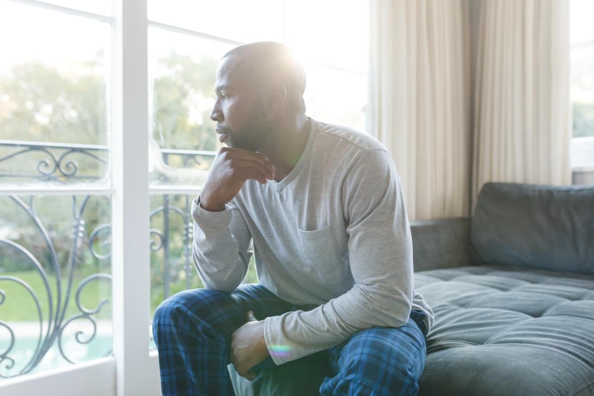 Concerned man looking out window thinking about opioid agonists and antagonists for addiction treatment