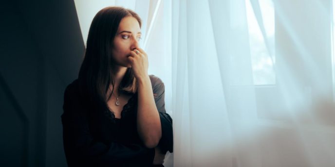 Concerned woman looking out window thinking about sublocade vs suboxone treatment