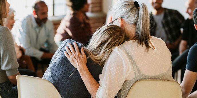 Two women in group therapy comforting each other while participating in drug rehab in Paris KY