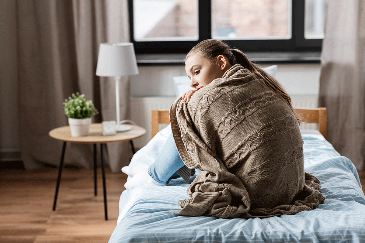 person wrapped up in blanket in bed while wondering what are the most addictive painkillers