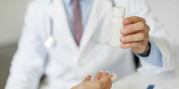 doctor holding up pill bottle explaining the benefits of medication assisted treatment