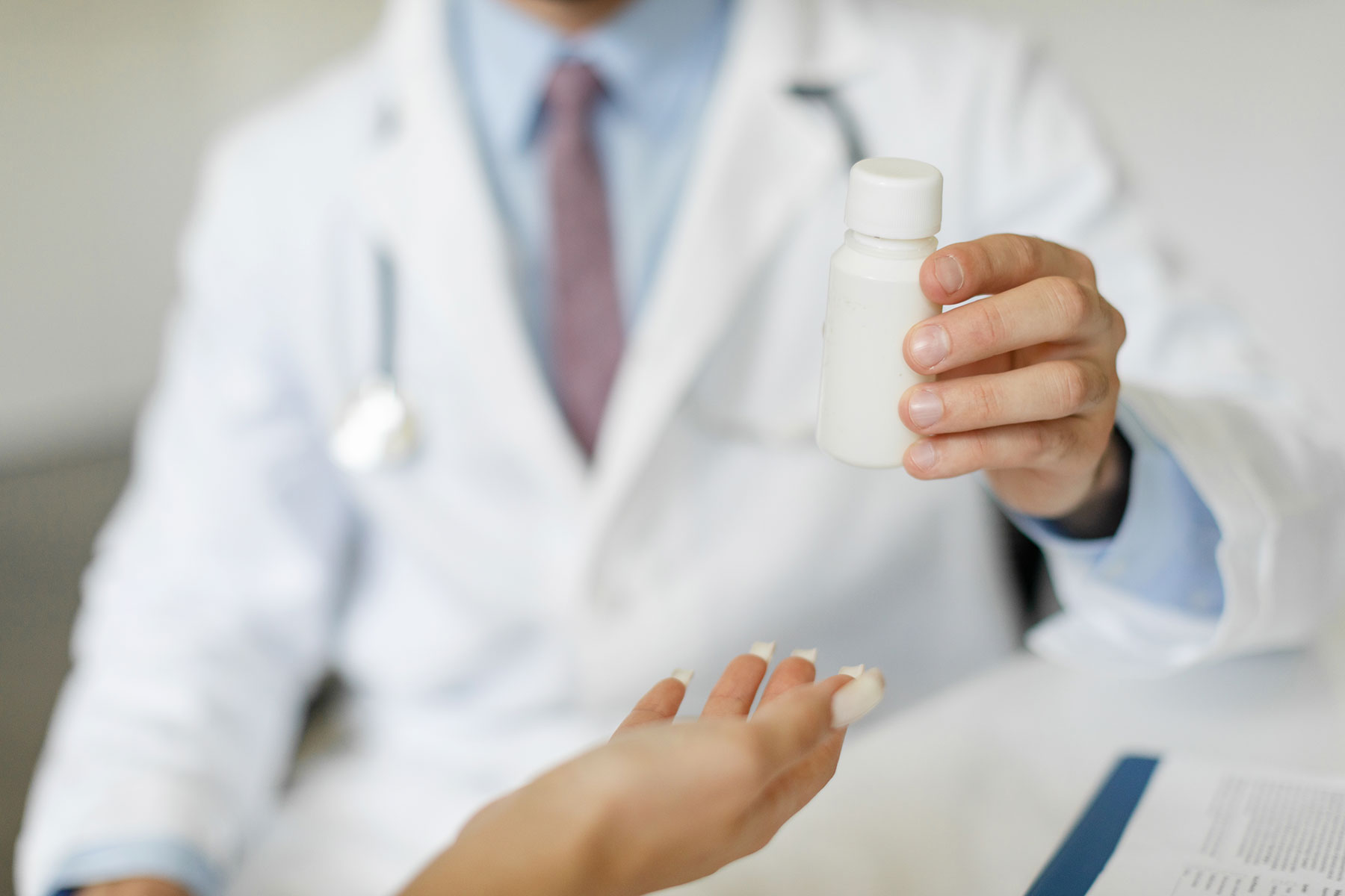 doctor holding up pill bottle explaining the benefits of medication assisted treatment