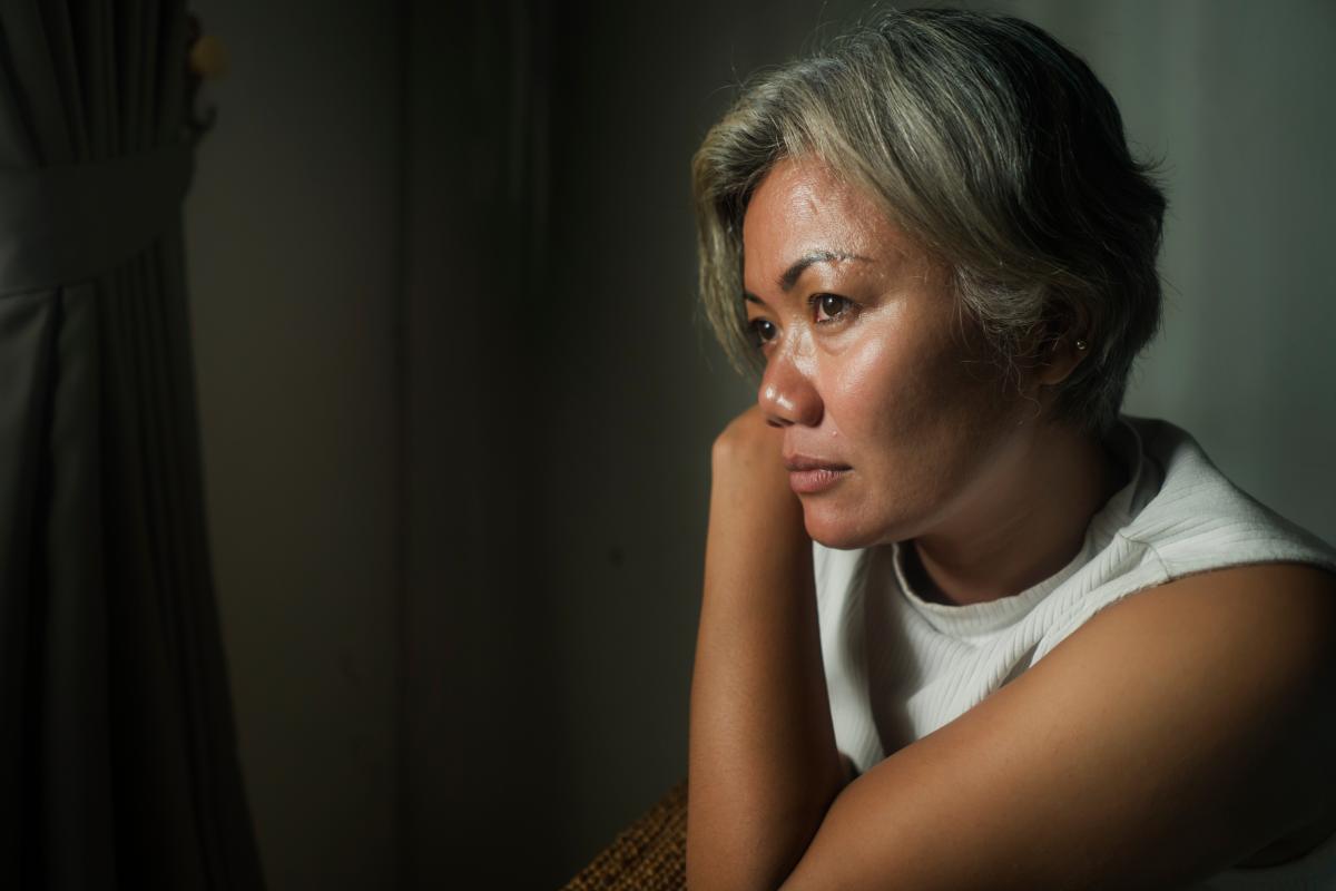 concerned person looking out window wondering about the impact of stress on addiction and recovery