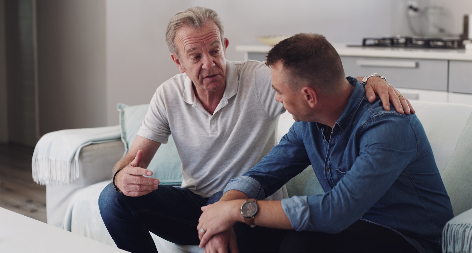 Sofa, old man and adult son bonding together in living room, conversation and support in home. Love, relationship and senior dad with man on couch, relax and discussion, family connection and advice.