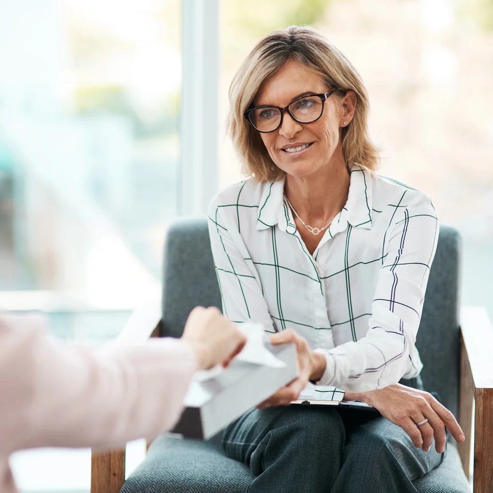 Woman handing tissues to another person
